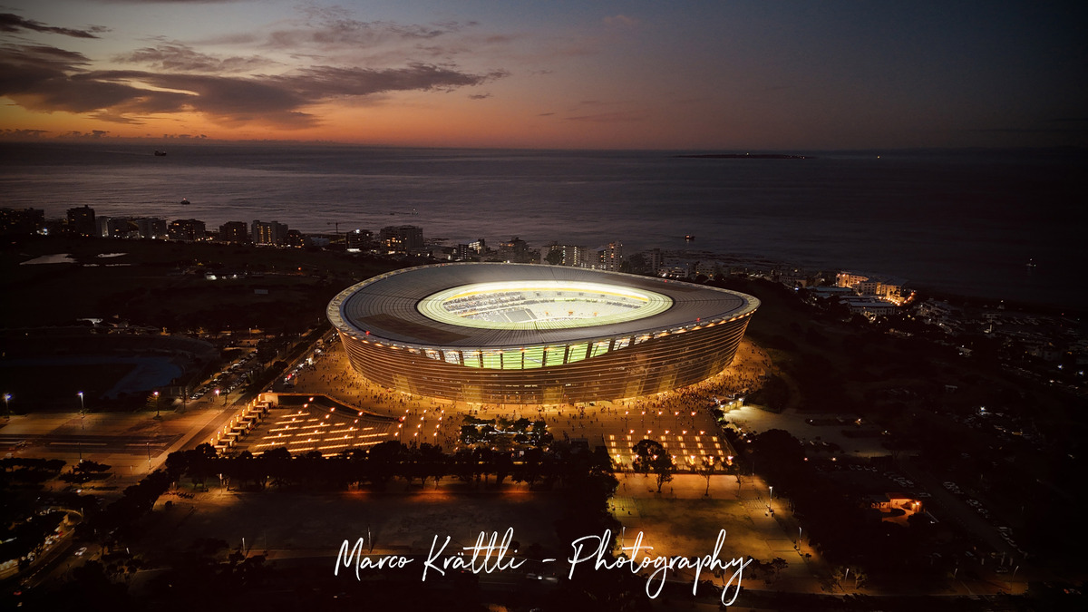 Cape Town Stadium glowing at dusk beside the Atlantic